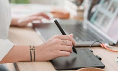 Graphiste utilisant un stylet et une tablette graphique devant son ordinateur portable