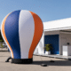 Montgolfière publicitaire auto-ventilée lestée devant un stand professionnel