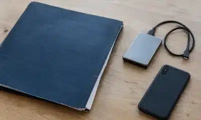 Dossier bleu, disque de sauvegarde et téléphone posé face contre une table.