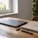 Ordinateur fermé, dossier en tissu et clé de sécurité sur un bureau éclairé par une fenêtre