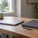 Ordinateur fermé, dossier de documents et stylo sur un bureau en bois.