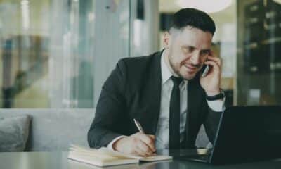 Professionnel prenant des notes dans un carnet pendant un échange téléphonique