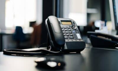 Téléphone de bureau noir posé près d’un écran dans un espace de travail