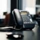 Téléphone de bureau noir posé près d’un écran dans un espace de travail
