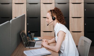 Une professionnelle portant un casque micro travaille sur un ordinateur portable.