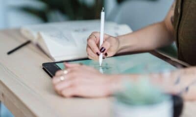 Designer dessinant au stylet sur une tablette posée sur un bureau en bois