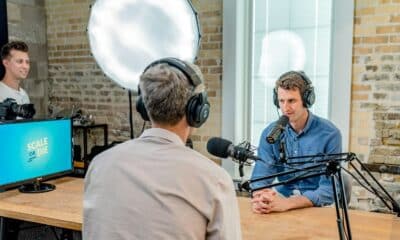 Deux interlocuteurs équipés de casques et de microphones enregistrent un podcast en studio.
