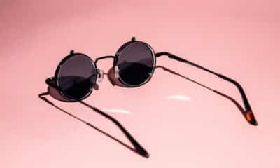 Lunettes de soleil rondes photographiées sur un fond rose avec leur ombre