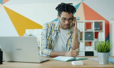 Professionnel au téléphone prenant des notes devant son ordinateur portable