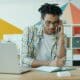 Professionnel au téléphone prenant des notes devant son ordinateur portable