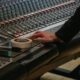 Une main règle une console de mixage audio en studio