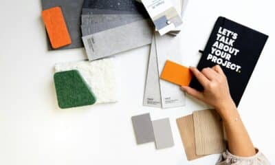 Main comparant un échantillon orange à des matières et des couleurs sur un bureau de création