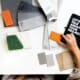 Main comparant un échantillon orange à des matières et des couleurs sur un bureau de création