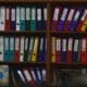 Classeurs colorés rangés sur des étagères en bois dans un bureau