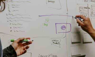 Deux personnes préparent un projet visuel devant un tableau blanc