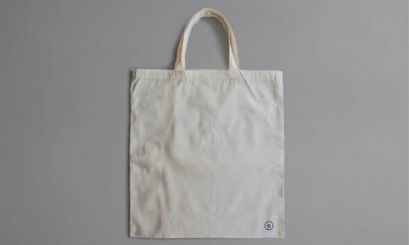 Sac en toile claire photographié de face sur un fond gris