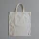Sac en toile claire photographié de face sur un fond gris